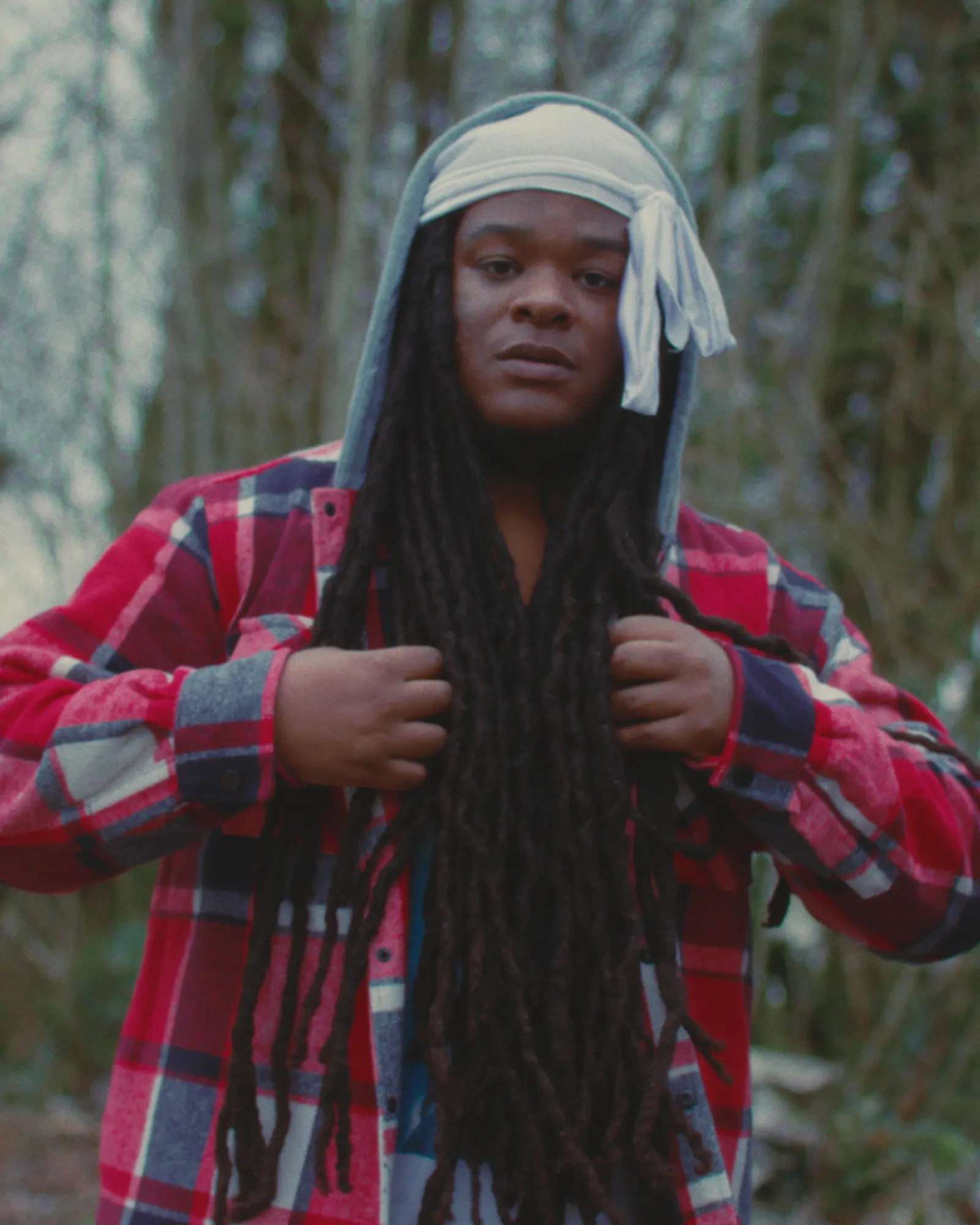 Malik Tijōn in a red flannel and hood